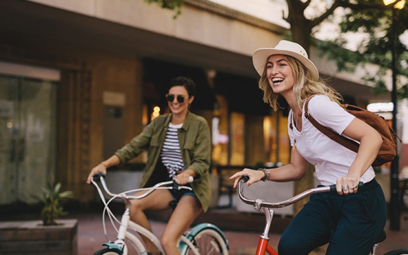 2 woman laughing riding bikes